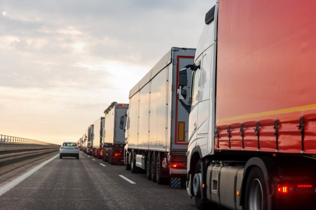 Kolumna ciężarówek na autostradzie przypomina o zasadach regulowanych przez prawo transportowe.