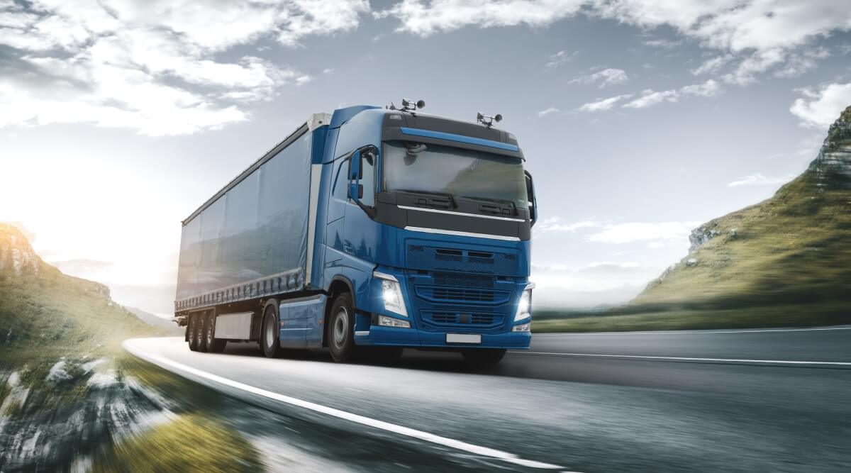 Niebieska ciężarówka jedzie po autostradzie, przestrzegając przepisy prawa transportowego.