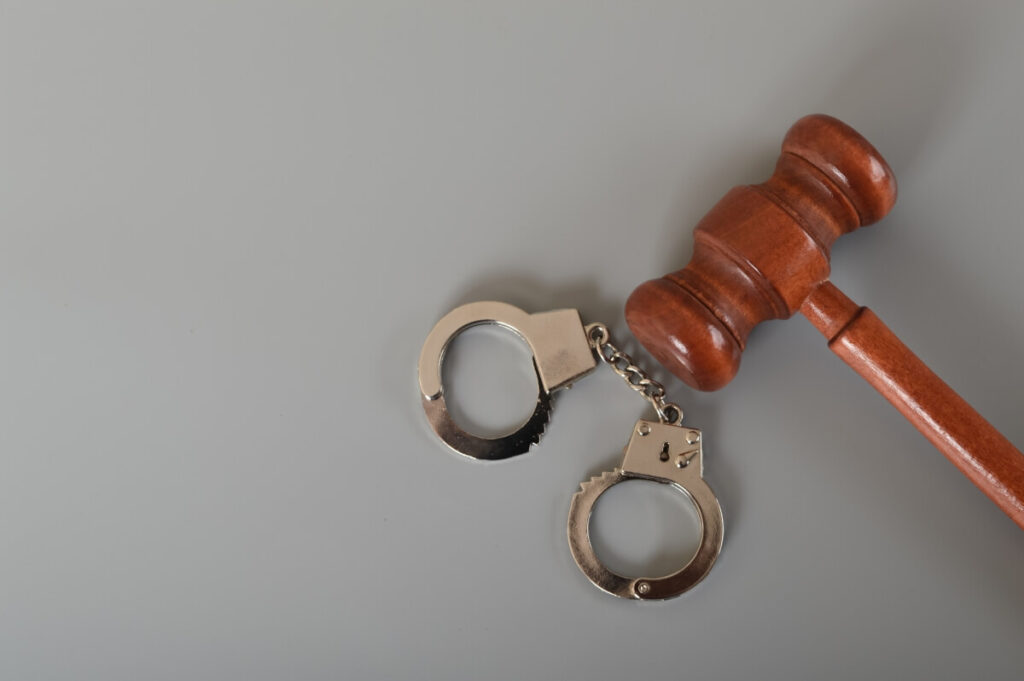 Młotek sędziowski i kajdanki jako symbol prawa karnego.