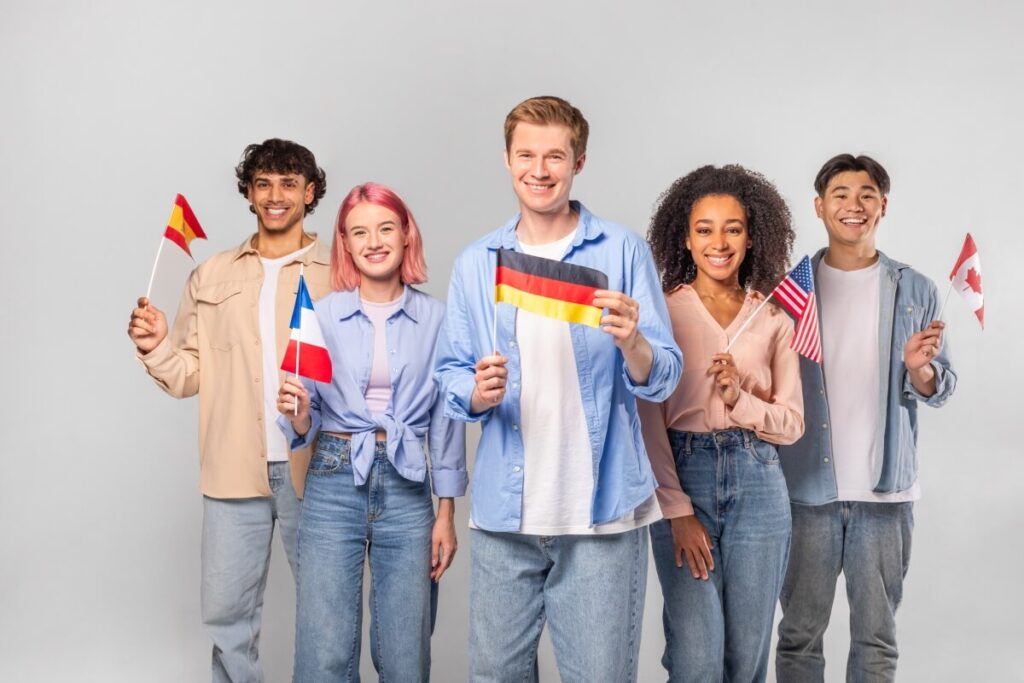 Grupa ludzi z różnymi flagami symbolizuje legalizację pracy cudzoziemców.
