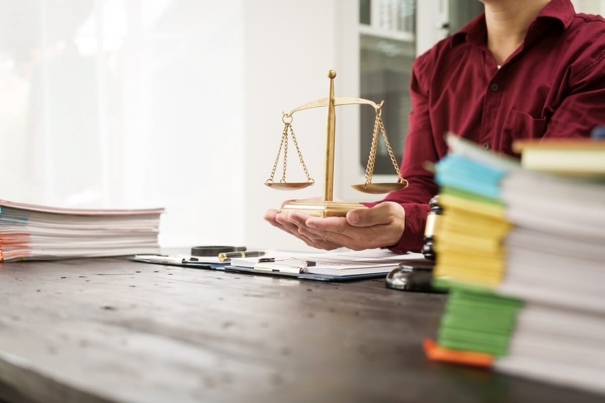 Na biurku leży waga symbolizująca prawo cywilne, otoczona dokumentami.