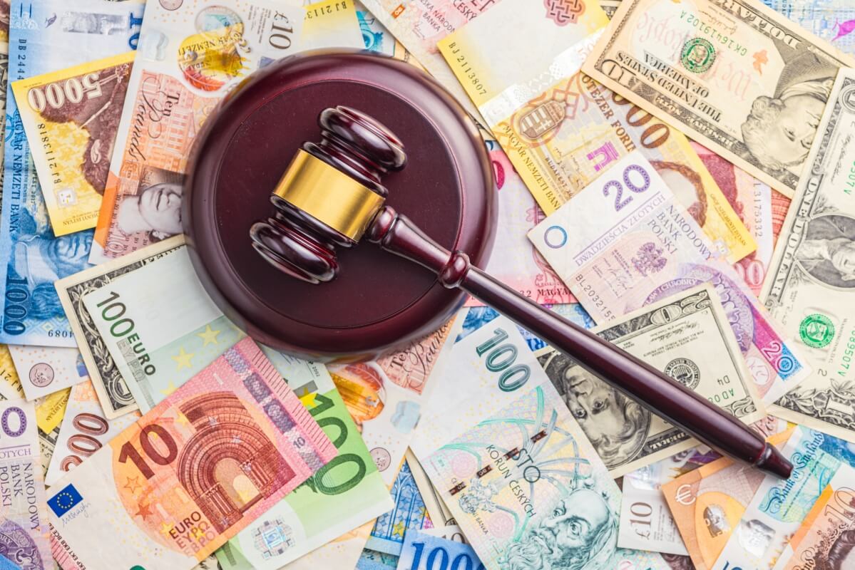Młotek sędziowski leży na stosie banknotów, symbolizując wpływ, jaki prawo gospodarcze ma na finanse.