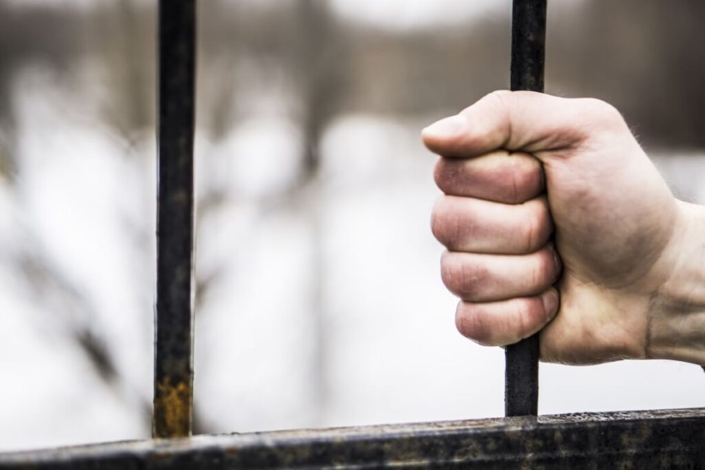 Ręka trzymająca kratę symbolizuje konsekwencje, jakie niesie za sobą prawo karne.